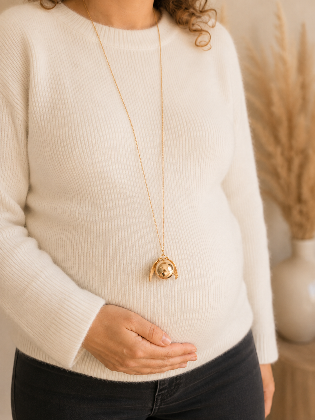 femme enceinte avec pull écri et bola de grossesse vif d'or avec deux ailes d'ange