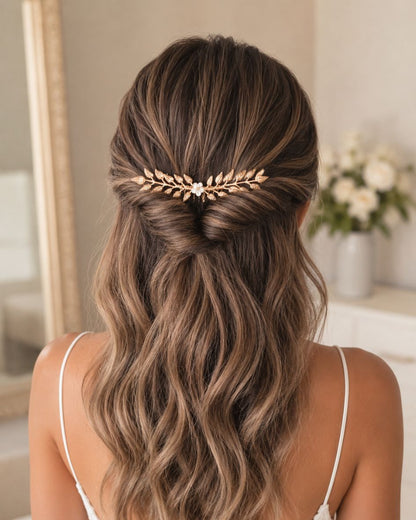 mariée avec cheveux semi-attachés et peigne feuilles dorée et fleur blanche